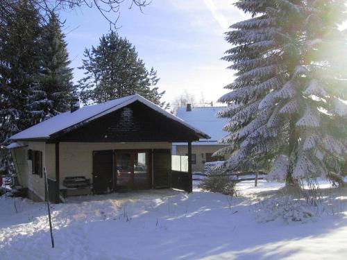 una pequeña casa en la nieve con un árbol en Charming Holiday Home in Liebenscheid by Forest en Liebenscheid