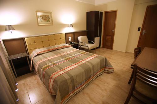 a bedroom with a bed and a desk and a chair at Soneca Plaza Hotel in Sao Paulo