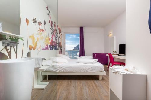 a hotel room with a bed and a window at Hotel Baia Azzurra - Lake Front in Nago-Torbole