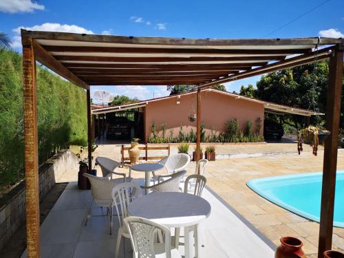 um pátio com mesas e cadeiras ao lado de uma piscina em CASA DA MONTANHA na Chácara Paraíso em Bananeiras