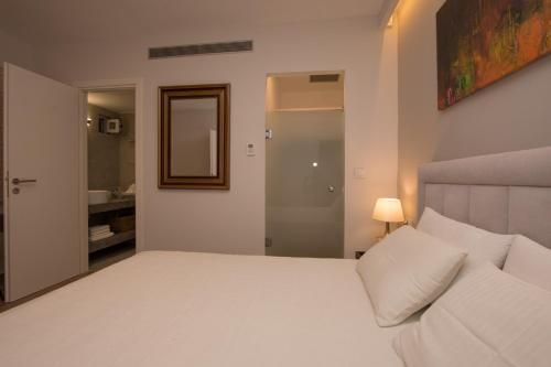 a bedroom with a large white bed and a bathroom at B4B Sea n' City in Zakynthos Town