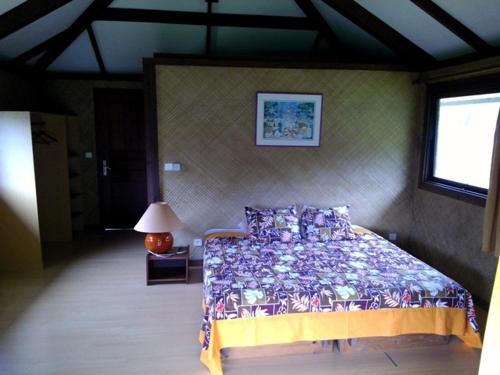 a bedroom with a bed and a lamp and a window at Le Relais de la Maroto in Pirae