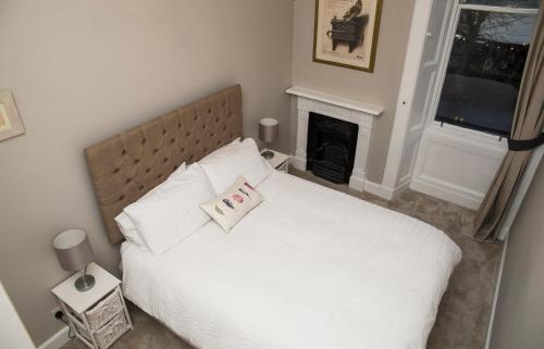 a bedroom with a white bed and a fireplace at Edinburgh, Stockbridge Apartment in Edinburgh