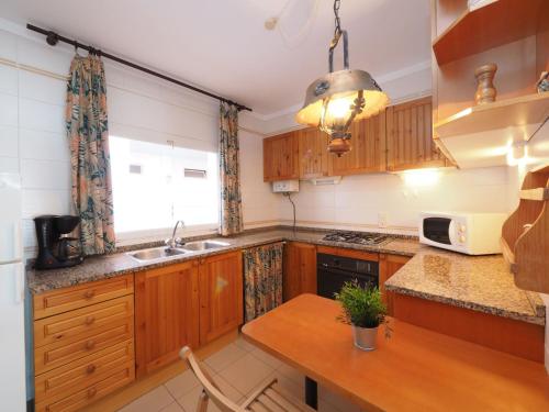 a kitchen with wooden cabinets and a table and a window at Apartment Roger de Flor-1 by Interhome in Llança