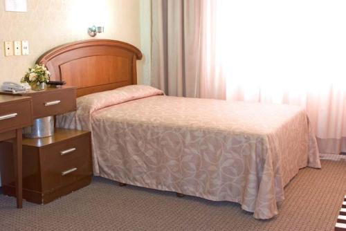 a bedroom with a bed with a dresser and a desk at Nuevo Hotel Alameda de Uruapan in Uruapan del Progreso