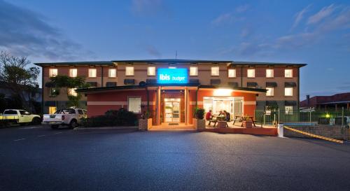a large building with a neon sign on the front of it at ibis Budget Coffs Harbour in Coffs Harbour