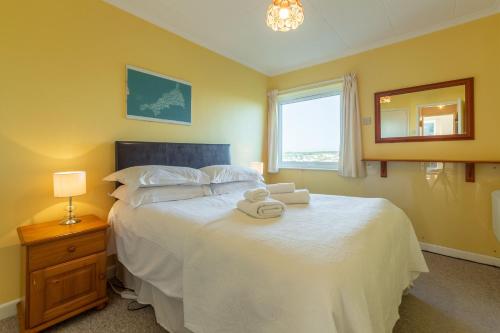 a bedroom with a large white bed with a window at 12 Westward Flats in Polzeath