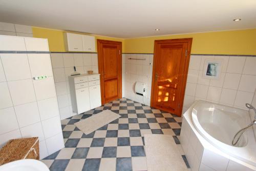 ein Badezimmer mit einer Badewanne und einem karierten Boden in der Unterkunft Ferienhaus mit 3 Schlafräumen Neu Sommersdorf SCHW 891 in Sommersdorf