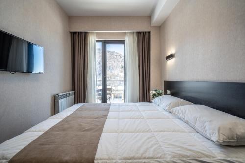 Cette chambre comprend un grand lit et une télévision. dans l'établissement Snow Pine Suite - 4 Star Resort, à Bakuriani