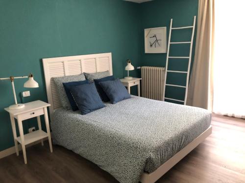 Un dormitorio con una cama con almohadas azules y una escalera en Au Rez de Jardin en Cholet