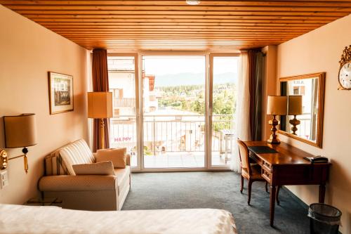 um quarto de hotel com uma secretária, uma cama e uma janela em Hillsite Smart Hotel Flims em Flims