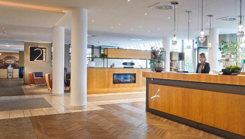 ライプツィヒにあるAtlanta Hotel Leipzigのフロントカウンターと女性1名が入ったホテルロビー
