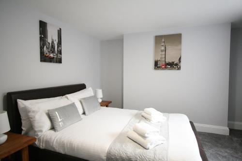 グロスターにあるNelson By The Docks Serviced Apartments by Roomsbookedの白いベッド1台、壁に2枚の写真が飾られたベッドルーム1室