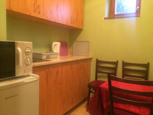 a kitchen with a microwave and a table and chairs at Dávid Apartman in Gárdony