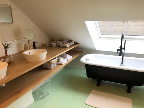 a bathroom with a sink and a bath tub at Lichtrijke loft bij restaurant Den Olifant in Ypres