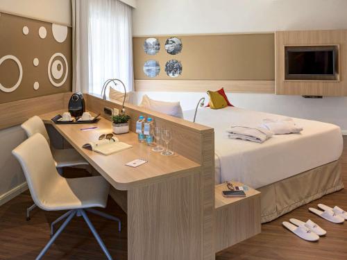 a hotel room with a bed and a desk at Mercure Sao Paulo Alamedas in Sao Paulo