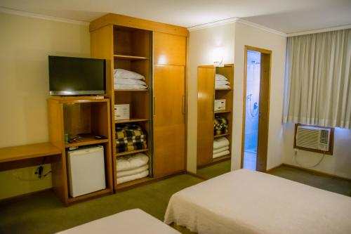 a hotel room with a bed and a television at Barbur Plaza Hotel in Ponta Grossa