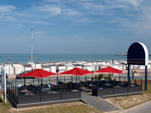 a restaurant with red umbrellas on the beach at Hôtel De La Plage in Calais