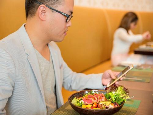 a man sitting at a table with a bowl of salad at Novotel Deira Creekside Dubai in Dubai