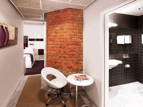 a bathroom with a white chair and a brick wall at Ibis Styles Stockholm Odenplan in Stockholm