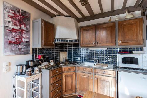- une cuisine avec des placards en bois et un four micro-ondes blanc dans l'établissement Au coeur de Sainte Catherine, à Honfleur