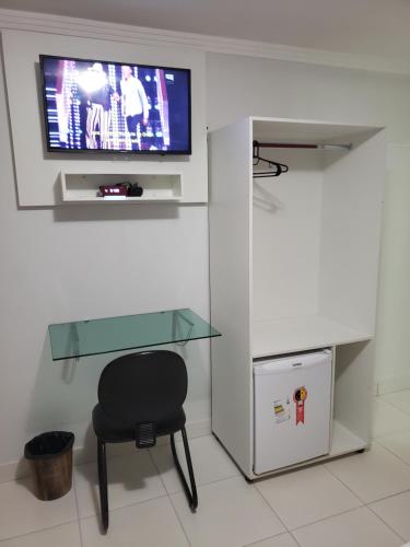 ゴイアニアにあるEuro Plaza Hotel - Próximo ao Aeroporto de Goiânia, Santa Genovevaのガラスのテーブル、椅子、テレビが備わる客室です。