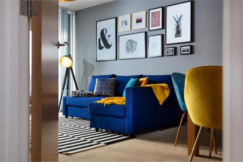 un sofá azul en una sala de estar con fotos en la pared en PENTHOUSE Plymouth Apartment- Sea View- Sleeps 7 - Private Parking - Habita Property, en Plymouth