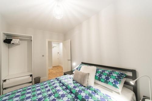 a bedroom with a large bed with blue and green pillows at Britannia House 1 bed apartment in Norwich