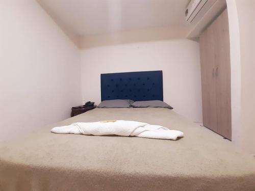 a white bedroom with a bed with a blue headboard at Villa Mary Hostal in Barranquilla