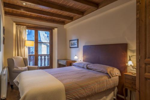 a bedroom with a bed and a chair and a window at Jireta by Totiaran in Barruera