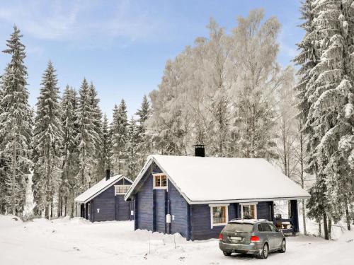a blue house with a car parked in the snow at Holiday Home Lakka by Interhome in Hauho
