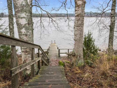 a wooden staircase leading to a lake with trees at Holiday Home Karhunluola by Interhome in Hauho