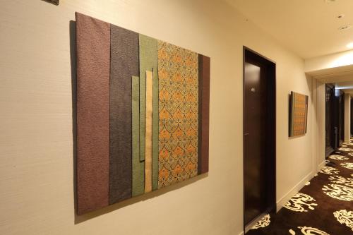 a hallway with three paintings on a wall at Centurion Hotel Grand Akasakamitsuke Station in Tokyo