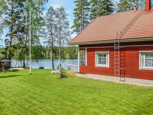 a red house with a yard next to a lake at Holiday Home Lauttavalkama by Interhome in Torvoila