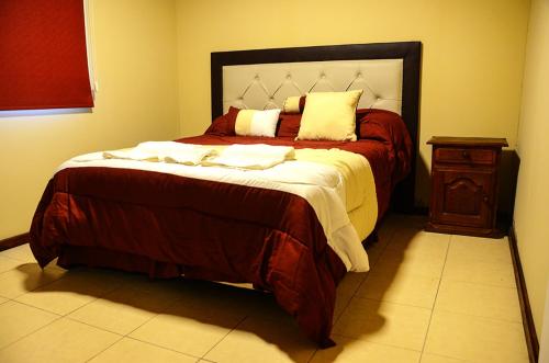 a bedroom with a large bed and a wooden night stand at La Isolina Club de Campo in Villa María