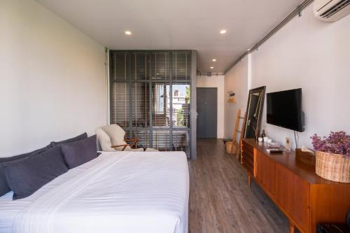 a bedroom with a white bed and a television at Iron32 Hotel in Chiang Mai