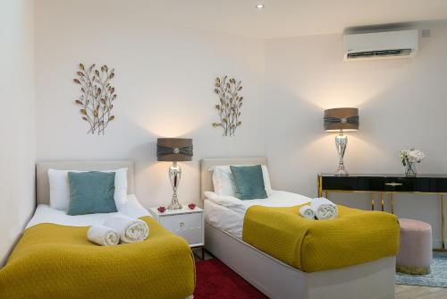 two beds with yellow cushions in a room at Cromwell road apartments in London