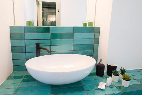 een badkamer met een witte wastafel op een blauwe tegelvloer bij Ninina Boutique Suites in Salerno