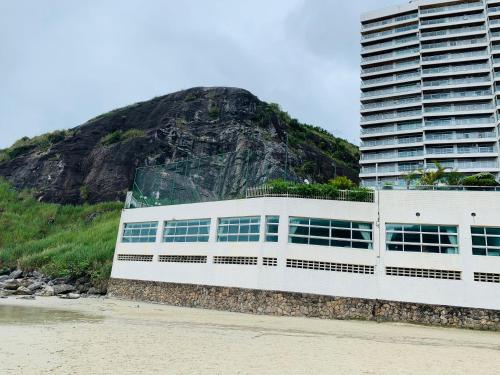 een gebouw op het strand naast een berg bij Apartamento Praia Guarujá in Guarujá