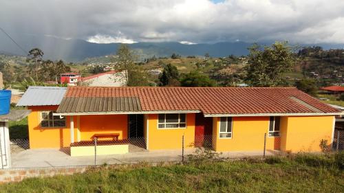 una casa amarilla con techo rojo en HOSPEDAJE CARIGAN, en Loja