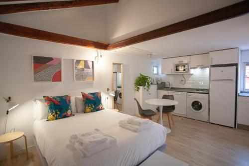 a bedroom with a large white bed and a kitchen at Gran Central Suites in Madrid