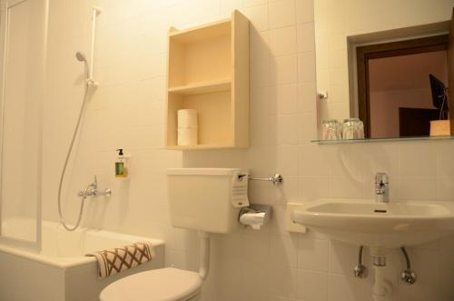 a white bathroom with a toilet and a sink at Landhotel Anna in Silandro