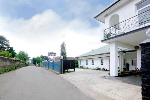 a white building with a fence next to a street at Sapu's Mountain breeze Nuwara Eliya in Nuwara Eliya