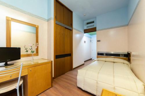 a bedroom with a bed and a desk with a television at Park Hotel in Rimini