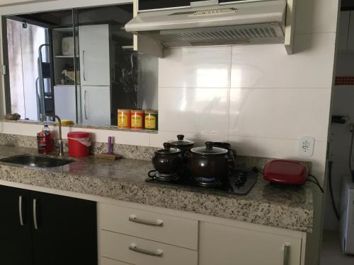 a kitchen counter with two pots on a stove at APARTAMENTO ACONCHEGANTE in Uberlândia