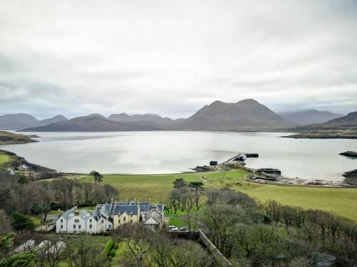 a house on a hill next to a body of water at Raasay House Hotel in Raasay