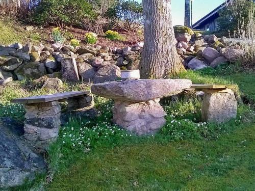 un banco de piedra sentado junto a un árbol en 8 person holiday home in LERUM, en Lerum