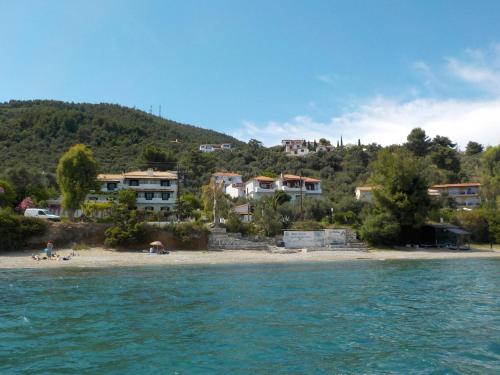 a beach with houses on a hill next to the water at Azalea in Megali Ammos