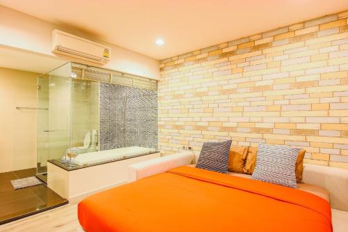 - une chambre avec un lit orange et une baignoire dans l'établissement The Crest Santora by Wanida monthly rate, à Hua Hin