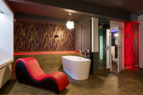 ein Badezimmer mit einer weißen Badewanne und einem roten Stuhl in der Unterkunft Yourplace Romantic Apartment with private patio in Krakau